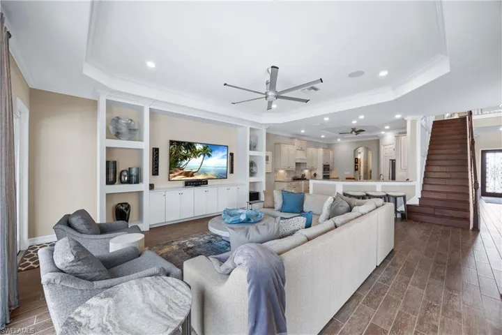 Living area featuring a ceiling fan, ornamental molding, wood tiled floors, a raised ceiling, and recessed lighting
