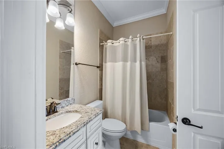 Full bathroom with crown molding, shower / bath combo, vanity, and a textured wall