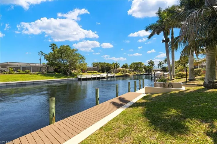 View of dock with a lawn and a water view