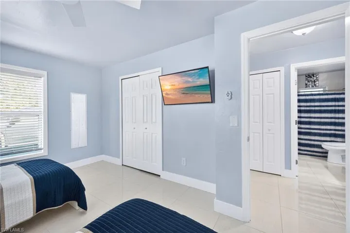 Bedroom with light tile patterned floors, a closet, ceiling fan, and ensuite bath