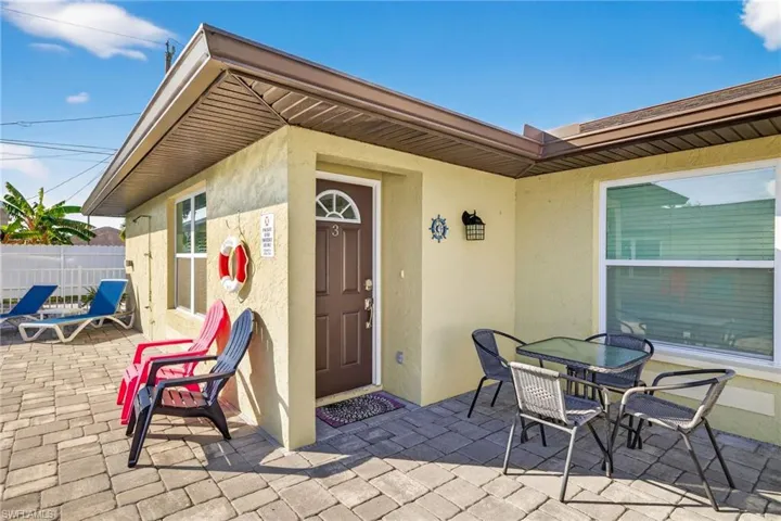 Entrance to property with stucco siding, a patio, and outdoor dining area