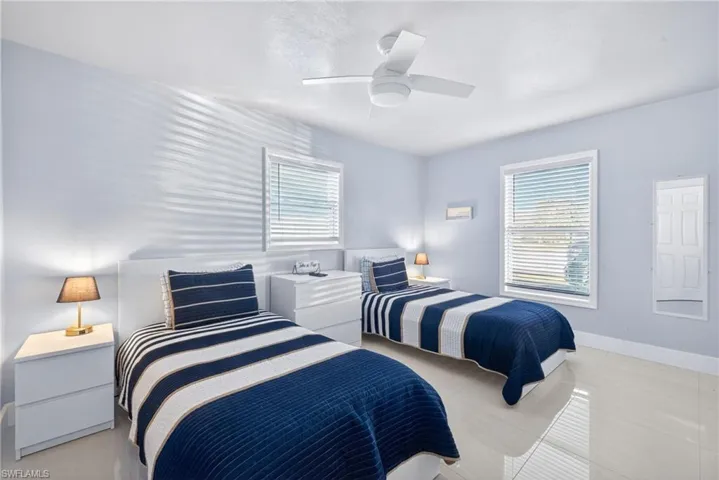 Bedroom with light tile patterned floors, ceiling fan, and multiple windows