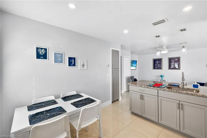 Kitchen featuring a ceiling fan, gray cabinets, light stone counters, hanging light fixtures, and recessed lighting