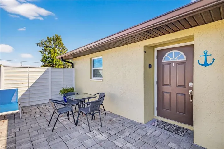Doorway to property featuring stucco siding, outdoor dining area, and a patio