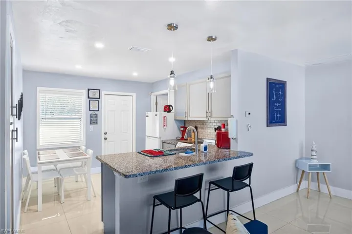 Kitchen with a kitchen breakfast bar, a peninsula, decorative light fixtures, recessed lighting, and light tile patterned flooring