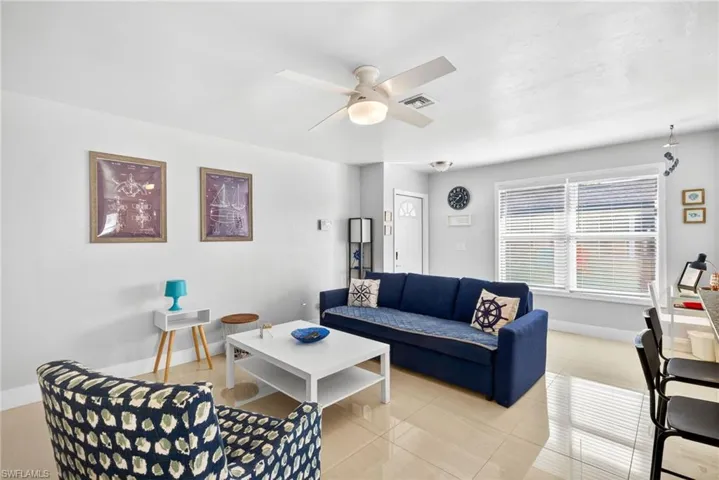 Living room with light tile patterned floors and a ceiling fan