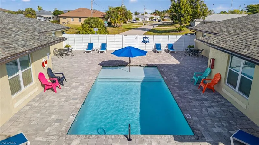 Community pool with a patio, a fenced backyard, and a residential view