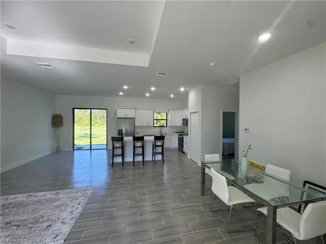Kitchen with stainless steel appliances, recessed lighting, white cabinetry, open floor plan, and a breakfast bar area