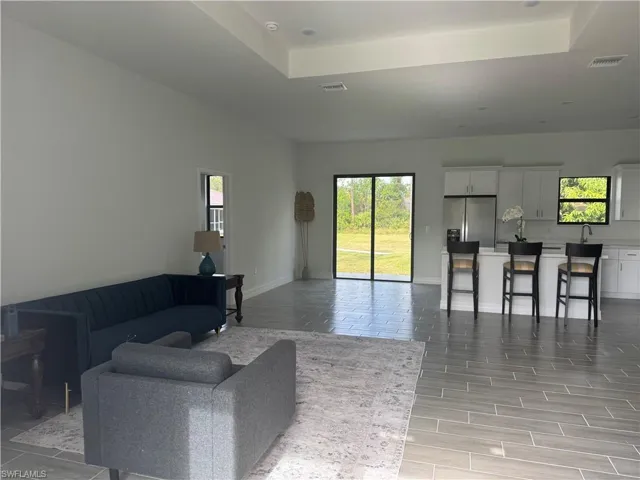 Living area featuring a tray ceiling, baseboards, and light wood-type flooring