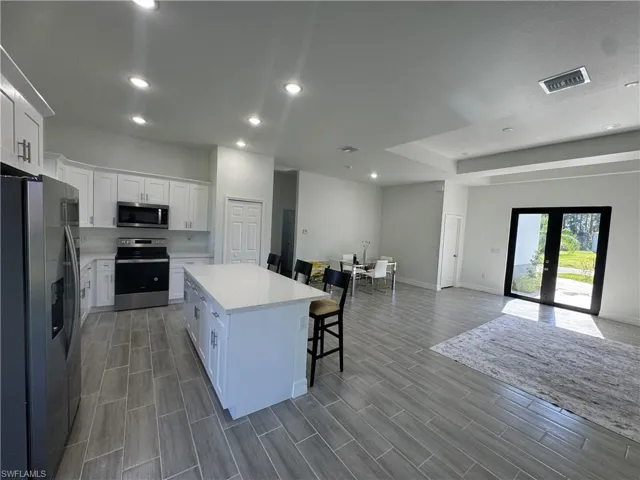 Kitchen featuring stainless steel appliances, a breakfast bar, a center island, open floor plan, and white cabinets