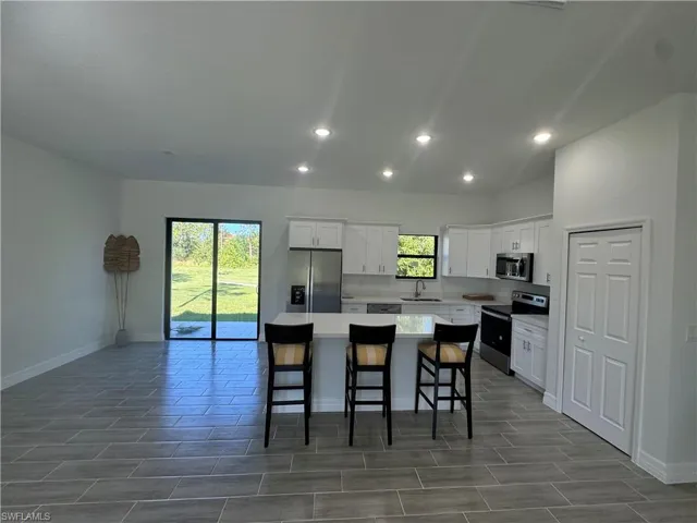 Kitchen featuring stainless steel appliances, a center island, baseboards, healthy amount of natural light, and recessed lighting
