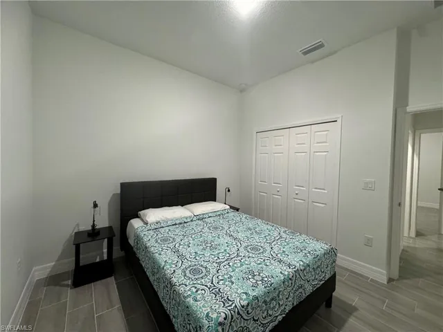 Bedroom with baseboards, a closet, and wood tiled floors