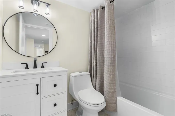 Full bathroom featuring toilet, shower / bath combination with curtain, and vanity