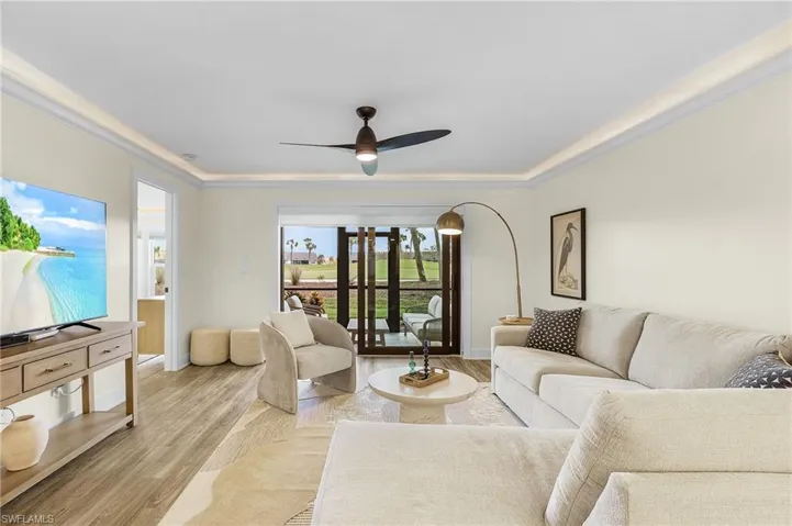 Living room featuring ornamental molding, light wood-type LVT flooring, and ceiling fan