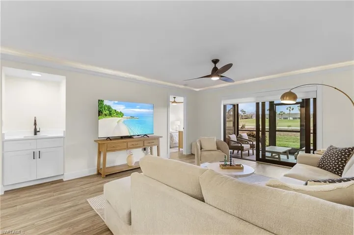 Living room featuring ornamental molding, sink, light wood-type LVT flooring, and ceiling fan