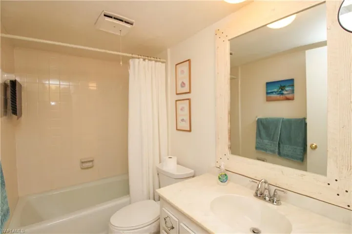 Full bathroom with toilet, vanity, and shower / bath combination with curtain
