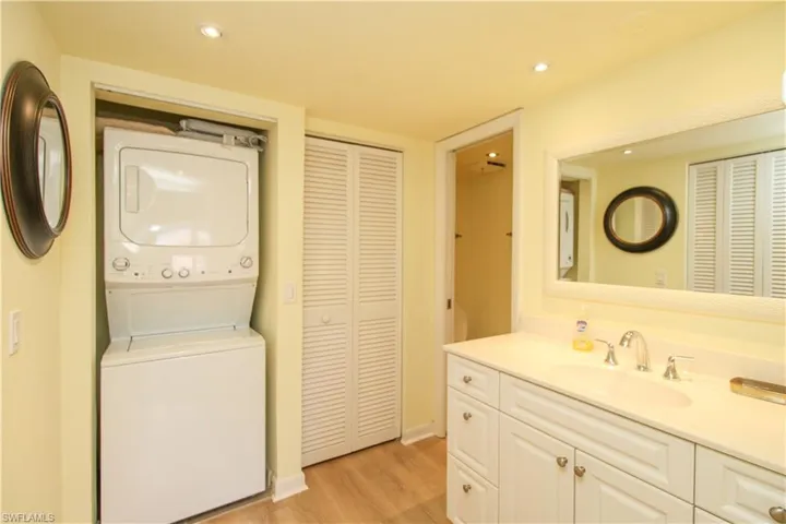 Laundry area featuring sink, light wood-type flooring, and stacked washer / drying machine