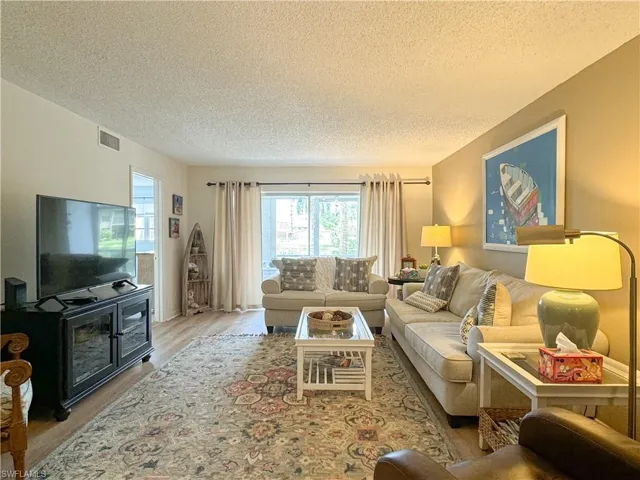 Living room with light wood-type flooring and a textured ceiling