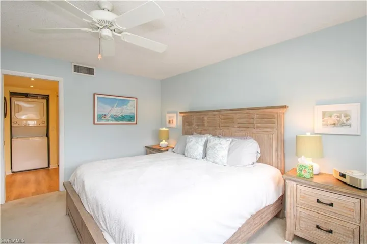 Carpeted bedroom with ceiling fan and stacked washing maching and dryer