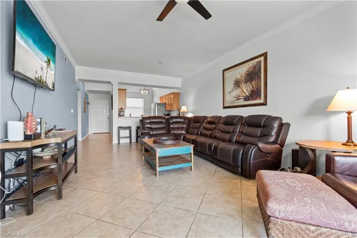Spacious living area featuring tile flooring on the diagonal and crown molding.