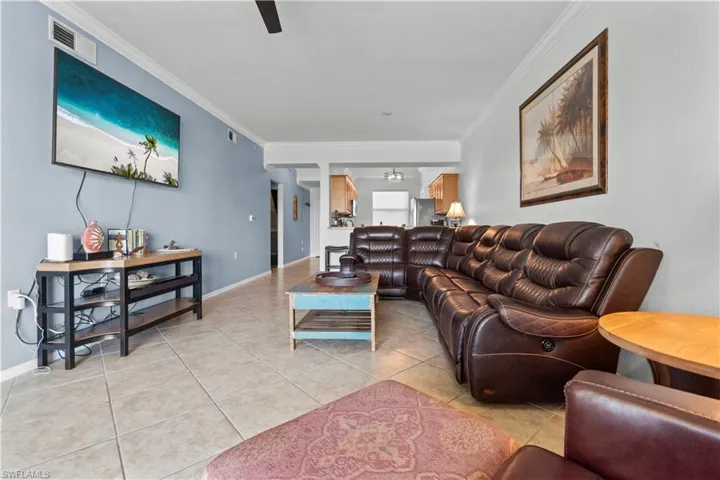 Spacious living area featuring neutral tile flooring and crown molding.
