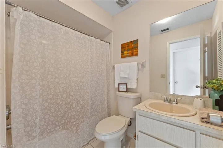 Full bathroom with a shower with curtain, visible vents, vanity, and toilet