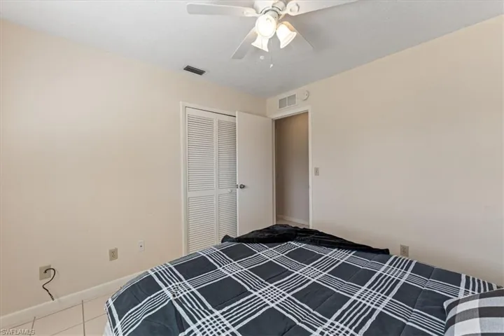 Unfurnished bedroom featuring tile patterned floors, a ceiling fan, visible vents, and a closet