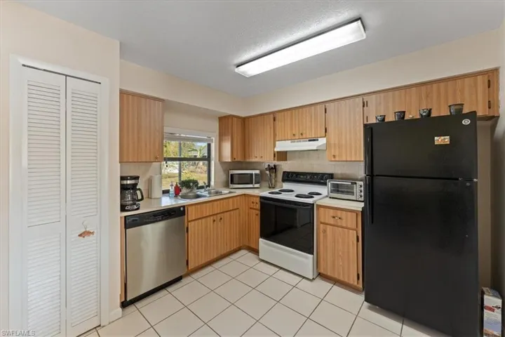 Kitchen featuring under cabinet range hood, light countertops, a sink, tasteful backsplash, and appliances with stainless steel finishes