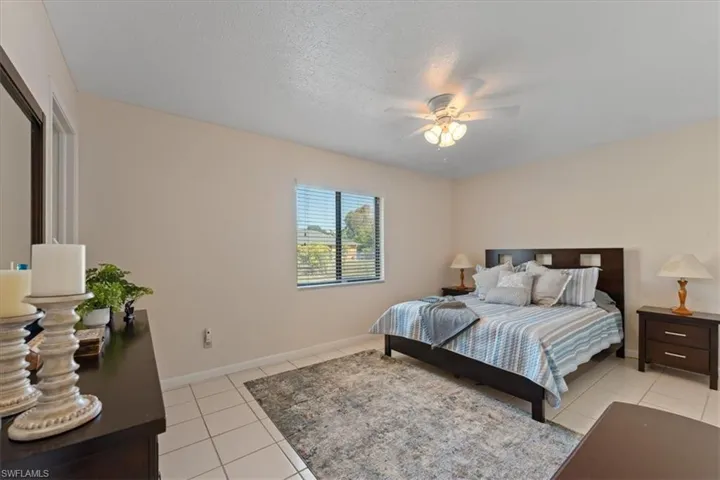 Bedroom with a ceiling fan, baseboards, and light tile patterned flooring