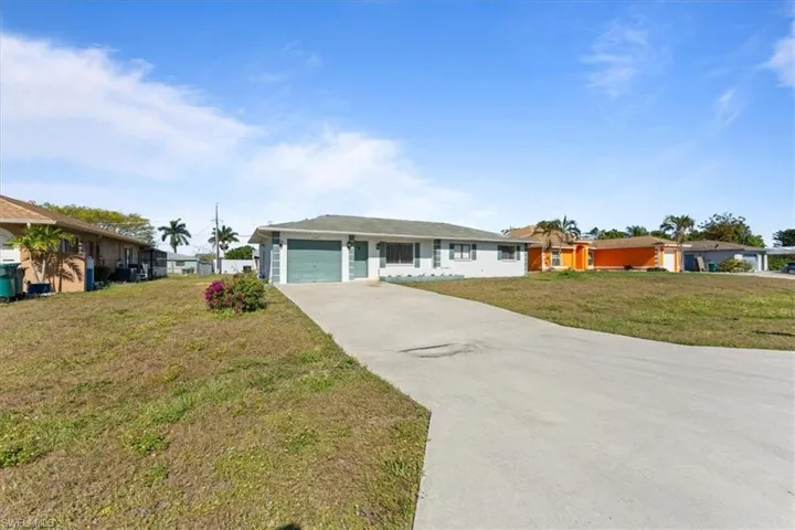 Ranch-style house featuring concrete driveway, a front lawn, and a garage