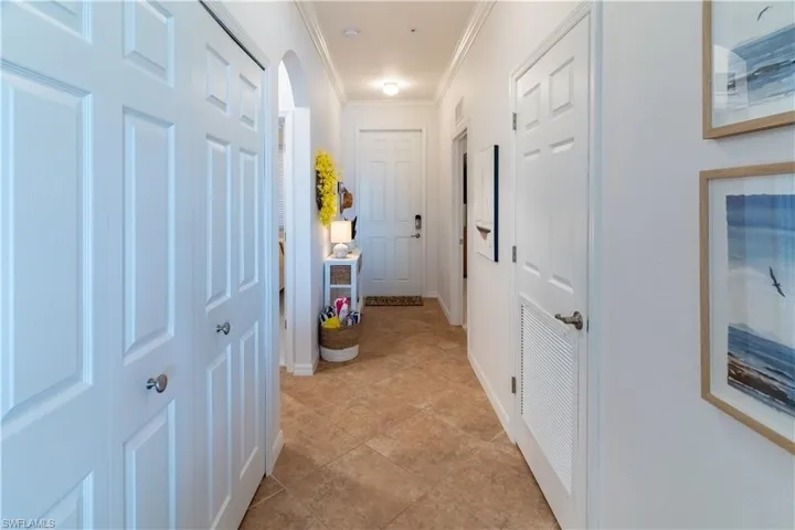 Hall featuring arched walkways, ornamental molding, and light tile patterned floors