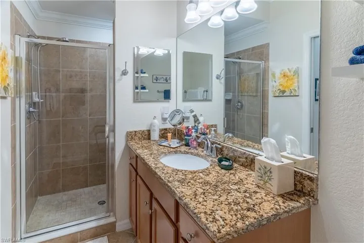 Bathroom featuring vanity, crown molding, a shower stall, and a textured wall