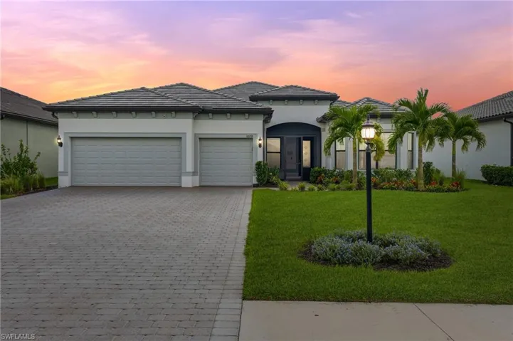 View of front of home featuring a front lawn, decorative driveway, a garage, stucco siding, and a tiled roof