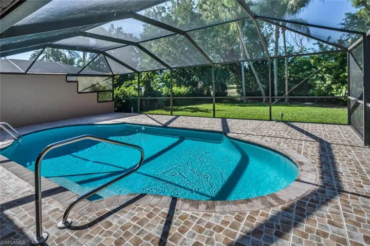 View of swimming pool with screened enclosure and shaded patio area