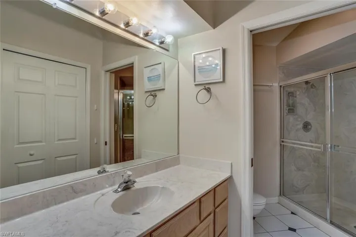 Bathroom with tile floors, a shower with shower door, toilet, and vanity