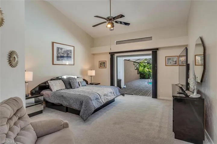 Bedroom with high vaulted ceiling, carpet, ceiling fan, and access to outside