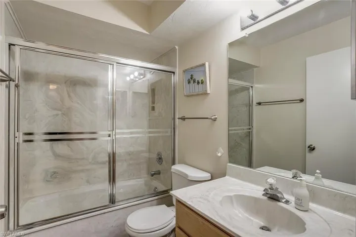 Full bathroom featuring enclosed tub / shower combo, toilet, and vanity