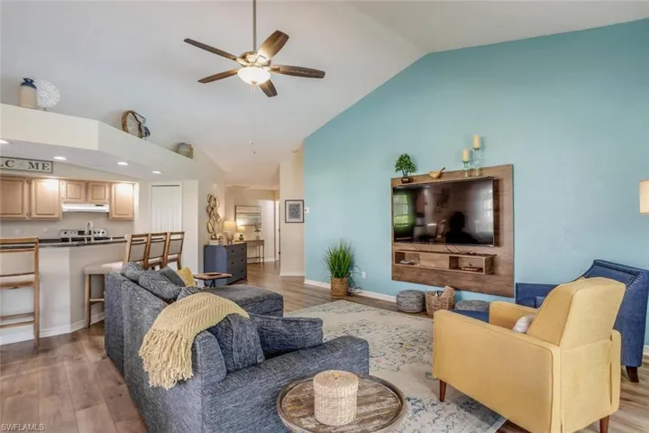 Living room featuring lofted ceiling, ceiling fan, and light hardwood / wood-style flooring