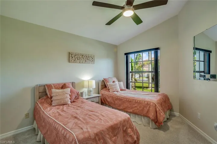 Carpeted bedroom with ceiling fan and lofted ceiling
