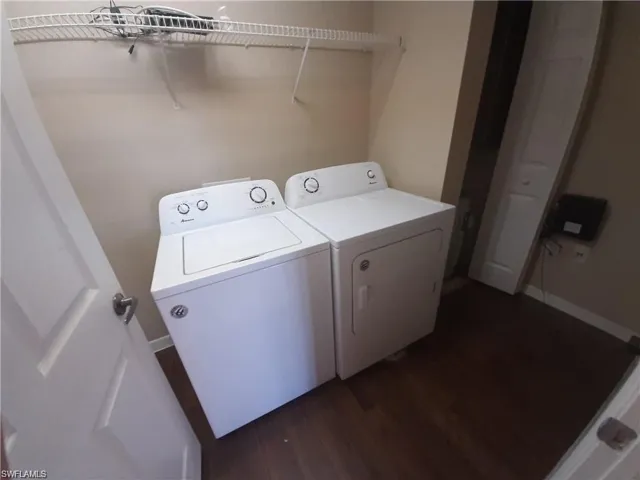 Clothes washing area featuring dark hardwood / wood-style flooring and washing machine and dryer