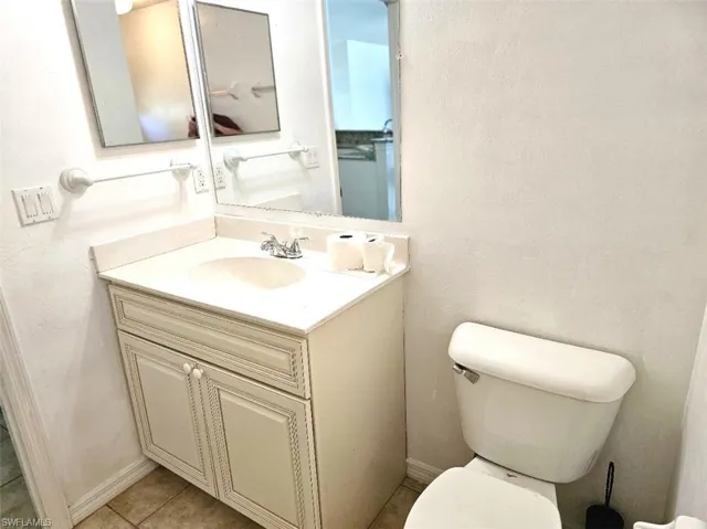 Half bathroom with vanity, a textured wall, and light tile patterned floors