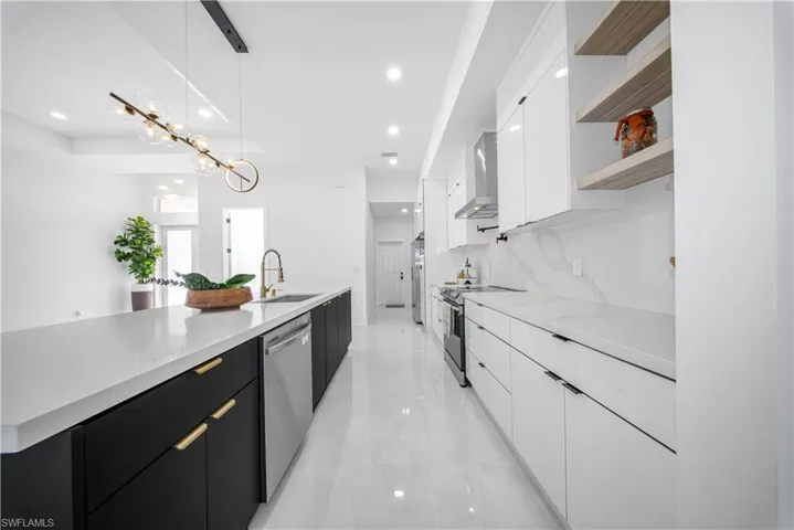 Kitchen featuring modern cabinets, dark cabinetry, white cabinetry, hanging light fixtures, and recessed lighting