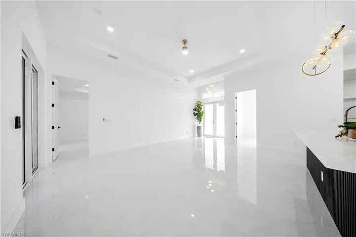 Unfurnished living room featuring a tray ceiling, french doors, recessed lighting, ceiling fan, and a chandelier