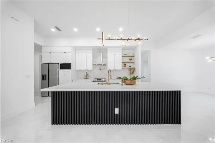 Kitchen featuring white cabinetry, backsplash, appliances with stainless steel finishes, open shelves, and a large island