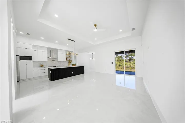Kitchen with white cabinets, modern cabinets, a tray ceiling, dark cabinetry, and recessed lighting