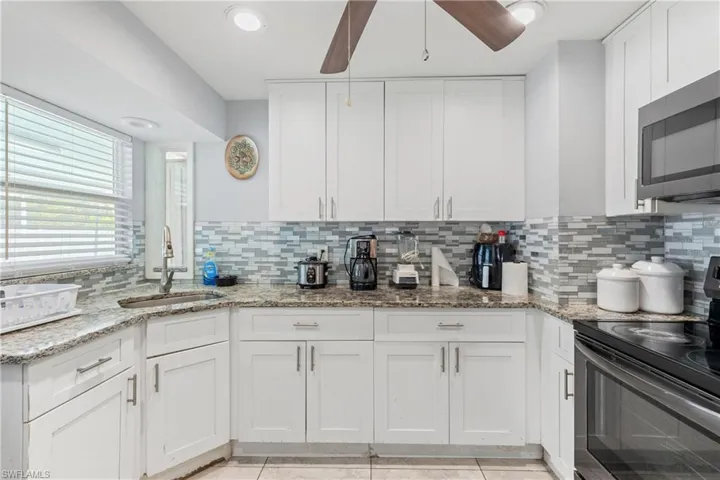 Kitchen with sink, black range with electric stovetop, ceiling fan, and tasteful backsplash