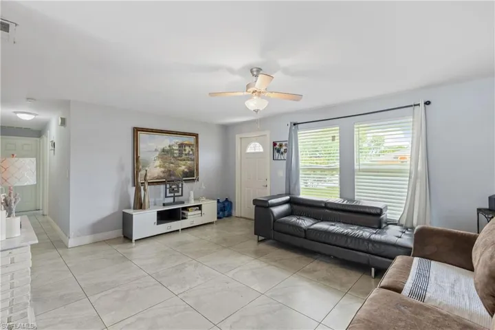 Living room featuring light tile patterned floors and ceiling fan