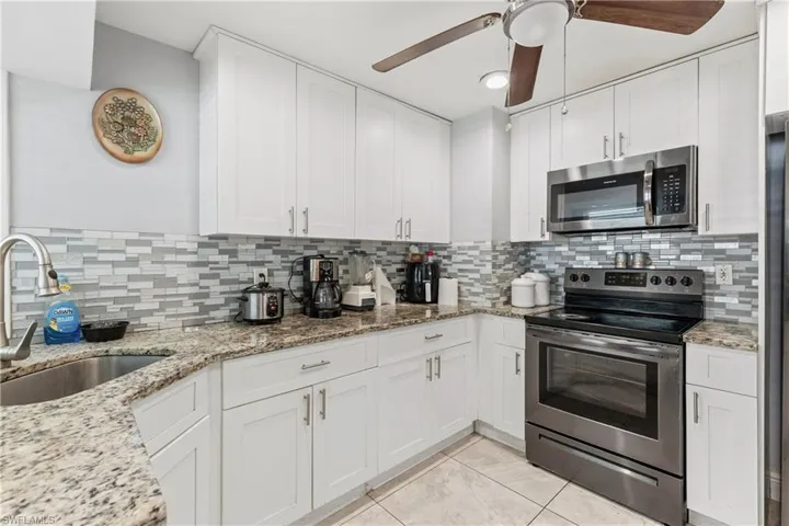 Kitchen with decorative backsplash, ceiling fan, and stainless steel appliances