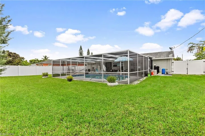 Rear view of house with a lanai, a yard, and a fenced in pool