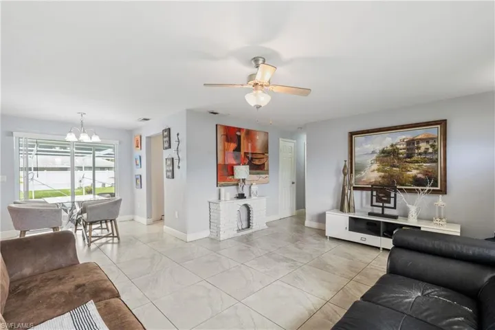 Living room with ceiling fan with notable chandelier and light tile patterned floors
